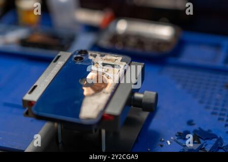Reparieren des hinteren Glases des Smartphones zeigt die Abbildung einen Techniker, der an einem Telefon arbeitet Stockfoto