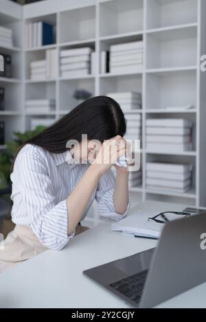 Geschäftsfrau plant eine Finanzprüfung, prüft Dokumente, während sie gegen das Burnout-Syndrom kämpft Stockfoto