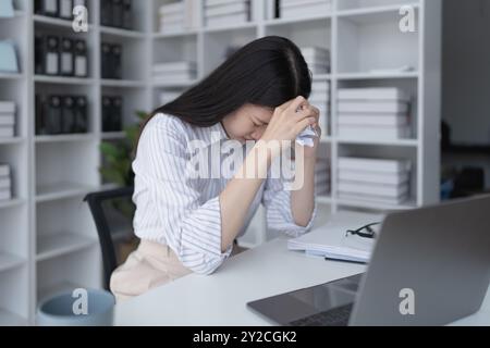 Geschäftsfrau plant eine Finanzprüfung, prüft Dokumente, während sie gegen das Burnout-Syndrom kämpft Stockfoto