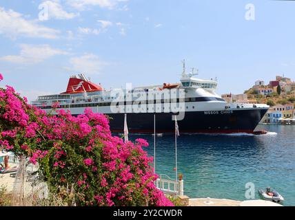 KASTELLORIZO, GRIECHENLAND-10. AUGUST 2018: Griechische Fähre fährt in den Hafen von Kastellorizo ein, mit Passagieren, die an einem heißen Sommertag Passagiere abholen und absetzen Stockfoto