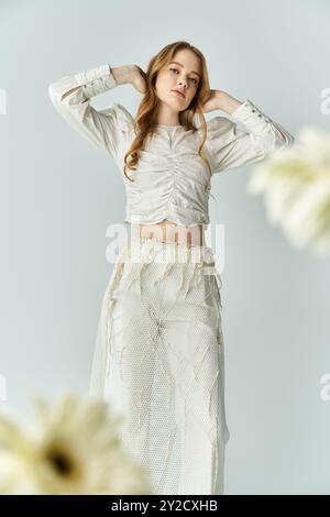 Eine schöne junge Frau in eleganter Kleidung interagiert mit zarten Blumen. Stockfoto