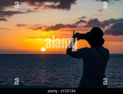 Touristenfrau, die mit Handy den Sonnenuntergang fotografiert, Pazifik, Galapagos Stockfoto