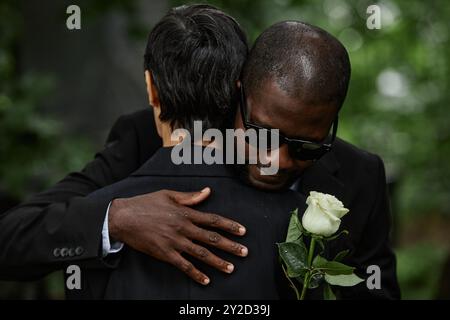 Mittlere Aufnahme eines erwachsenen Schwarzen Mannes in Sonnenbrille, der eine ältere Frau umarmt, während er über den Verlust eines geliebten Menschen auf dem Friedhof trauert Stockfoto