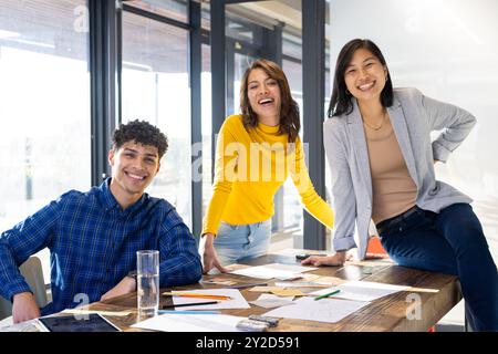 Lächelndes, vielfältiges Team, das im Büro mit Skizzen und Notizen an einem Innenarchitekturprojekt arbeitet Stockfoto