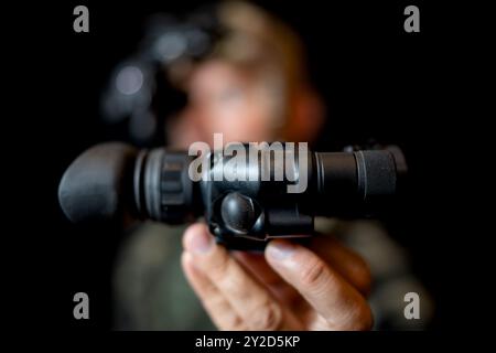 Ein Soldat der Spezialkräfte mit einem Nachtsichtgerät in der Hand auf schwarzem Hintergrund. Stockfoto