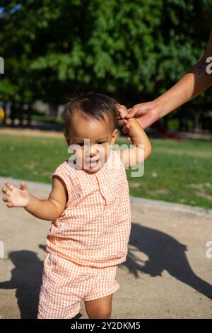 Die 1-jährige Latina macht ihre ersten Schritte in einem Park im Freien Stockfoto