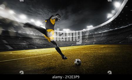 Als das Spiel nahe am Ende ist, konzentrierte er sich auf den Sieg des Fußballspielers Dribbling und tritt den Ball auf dem grünen Feld mit voller Kraft, um unter dem elektrischen G des Stadions Tor zu erzielen Stockfoto