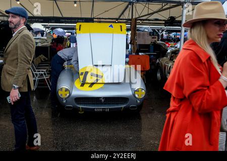 Stilvoll...Goodwood Revival 2024. Im Paddock sitzt ein Ferrari, der für das Rennen vorbereitet wurde, unter den Besuchern der alten Zeit. Stockfoto