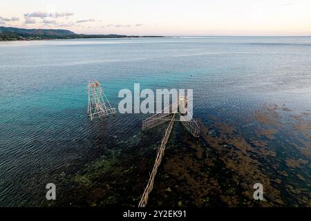 Aus der Vogelperspektive auf interessante hölzerne Angeltürme und eine Bambusfalle in Pfeilform an der Küste nördlich von Makassar in Sulawesi, Indonesien Stockfoto