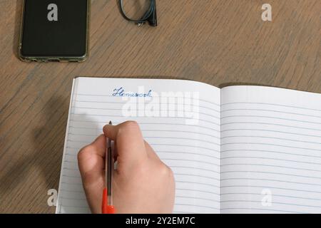 Hausaufgaben. Der Teenager wird während des Unterrichts telefonisch abgelenkt Stockfoto