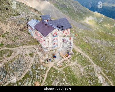 Die Breslauer Hütte liegt ruhig in den Otztaler Alpen, umgeben von rauem Berggelände. Besucher treffen sich draußen und genießen die atemberaubende Aussicht auf die Berge an einem sonnigen Tag in der österreichischen Wildnis. Stockfoto