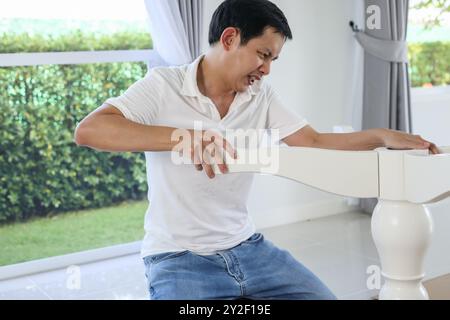 Asiatischer Mann, der weiße Tischmöbel zu Hause zusammenbaut Stockfoto