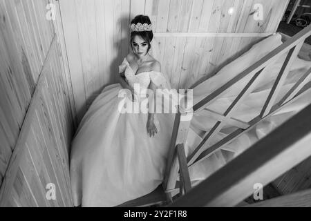 Bezaubernde Brautelegantheit: Ein Schwarzweiß-Porträt einer Braut auf Holztreppe. Stockfoto