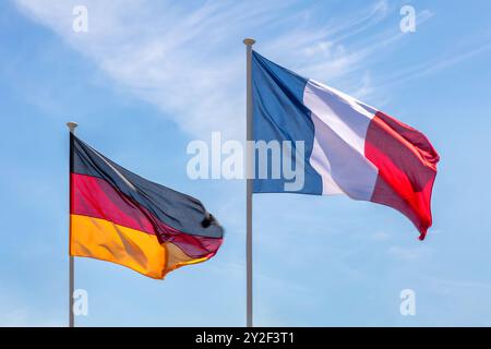 Französische und deutsche Flagge vor einem blauen Himmel schwenken Stockfoto
