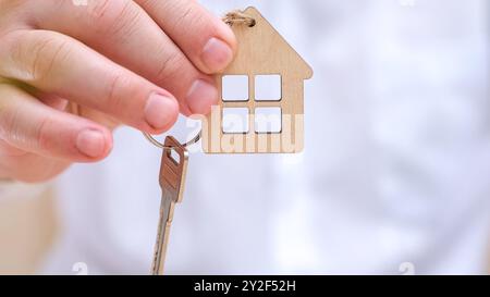 Männliche Hand, die den Hausschlüssel aus der Nähe hält. Wohnungsdarlehen, Hypotheken, Investitionen, Miete, Immobilien Stockfoto