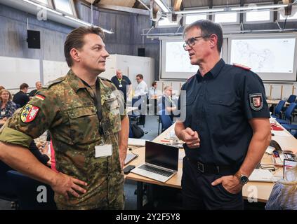 Kiel, Deutschland. September 2024. Dirk Hundertmark (r), Leiter Krisenmanagement im Innenministerium, und Matthis Beck, Oberstleutnant der Bundeswehr, sprechen im Operationssaal während einer Pressekonferenz während der Planungsübung für das Krisenteam zum Szenario „Sturmflut in der Ostsee“. Katastrophenschutzbeamte bereiten sich noch immer auf den Einsatz vor, falls es zu einem schweren Sturmflut in der Ostsee kommt, wie es im Oktober mit einer Planübung in Kiel bis Donnerstag der Fall war. Quelle: Christian Charisius/dpa/Alamy Live News Stockfoto