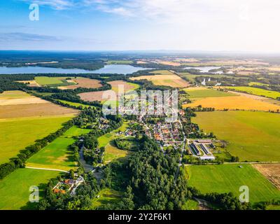 Ein weitläufiger Blick aus der Luft zeigt die ruhige ländliche Landschaft rund um Trebon, Tschechien, mit üppigen grünen Feldern, gewundenen Flüssen und kleinen Dorfgruppen unter einem klaren blauen Himmel. Stockfoto