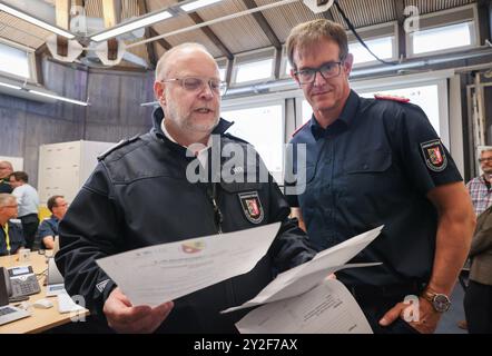 Kiel, Deutschland. September 2024. Dirk Hundertmark (r), Leiter des Referats Krisenmanagement im Innenministerium, und Svend Rix, stellvertretender Leiter des Referats Krisenmanagement und heutiger Übungsleiter, sprechen im Operationssaal bei einer Presseveranstaltung während der Planungsübung für das Krisenreferat zum Szenario "Sturmflut in der Ostsee". Mit einer Planungsübung bereiten sich Katastrophenschutzbeamte bis Donnerstag in Kiel auf den Einsatz im Falle einer schweren Sturmflut in der Ostsee wie im Oktober vor. Quelle: Christian Charisius/dpa/Alamy Live News Stockfoto