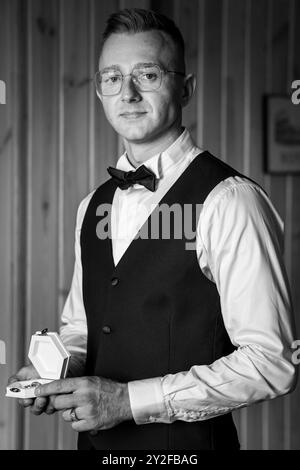 Eleganter Gentleman mit zarter Schmuckschatulle in klassischem Schwarz-weiß-Porträt. Stockfoto