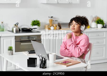 Eine junge Frau genießt ihre Zeit zu Hause, in Gedanken verloren mit Kopfhörern. Stockfoto