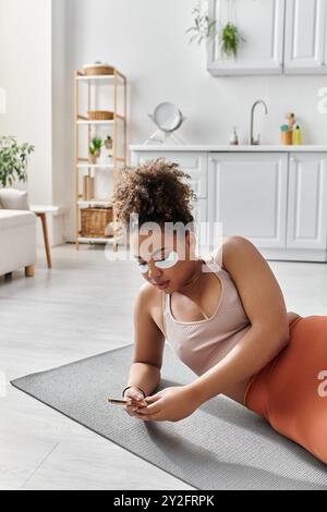 Eine junge Frau entspannt sich auf ihrer Yogamatte, während sie sich verwöhnt. Stockfoto