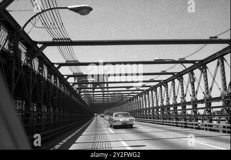 AJAXNETPHOTO. - JULI 1975. NEW YORK, USA. - AUF DEM FAHRZEUGDECK DER BROOKLYN BRIDGE, DIE DEN EAST RIVER VON DER BROOKLYN SEITE IN RICHTUNG LOWER MANHATTAN ÜBERSPANNT. FOTO: JONATHAN EASTLAND/AJAX REF:750024 11A 92 Stockfoto