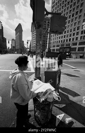 AJAXNETPHOTO. OKTOBER 2000. MANHATTAN, NEW YORK CITY, USA. GESTERN HEUTE UND MORGEN LESEN WIR ZEITUNG AUS DER MÜLLTONNE IN DER NÄHE DES FLATIRON-GEBÄUDES AN DER KREUZUNG VON BROADWAY UND 5TH AVENUE. FOTO: JONATHAN EASTLAND/AJAX REF:3547 12 0A Stockfoto