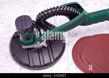 Wandschleifer mit Teleskopgriff und Schleifpapier zum Glätten und Schleifen von Wänden auf grauweißem Hintergrund. Stockfoto