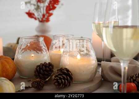 Brennende Kerzen, Weingläser und Herbstdekor auf dem Tisch, Nahaufnahme Stockfoto