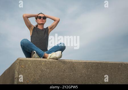 Frau, die draußen sitzt, Hände auf dem Kopf, emotionales Stress-Konzept Stockfoto