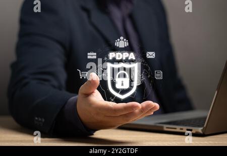 Mann mit einem Sicherheitsschild-Symbol mit einem Vorhängeschloss in der Mitte. Konzept des Datenschutzgesetzes: PDPA. Es ist ein Rechtsgrundsatz, um zu verhindern Stockfoto