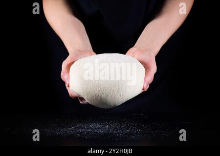 Köcherhände und roher Teig aus Nahaufnahme auf schwarzem Hintergrund. Das Konzept von Backen und Gebäck Stockfoto