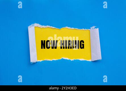 Jetzt ist die Einstellungsnachricht auf gerissenem blauem Papier mit gelbem Hintergrund geschrieben. Symbol „Conceptual Now Hiring“. Kopierbereich. Stockfoto