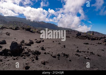 Blick über ein mit vulkanischer Asche bedecktes Lavafeld zu grünen Berghängen in der Nähe von Las Manches, La Palma Stockfoto