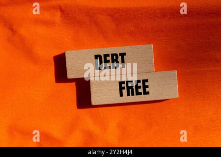 Schuldenfreie Botschaft auf Holzblöcken mit orangem Hintergrund. Konzeptionelles schuldenfreies Symbol. Kopierbereich. Stockfoto