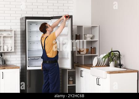 Männlicher Arbeiter repariert Kühlschrank in der Küche Stockfoto