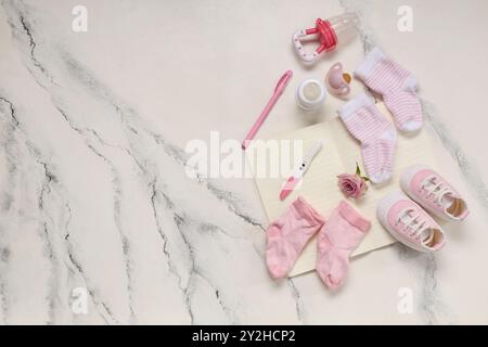 Komposition mit Babysocken, Brustwarzen, Schwangerschaftstest und Notizbuch auf grunge weißem Hintergrund Stockfoto