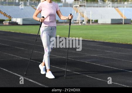 Schöne reife Frau, die mit Gehstöcken im Stadion trainiert, Nahaufnahme Stockfoto