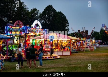 Eine Gruppe von Menschen bei einer Reihe von Vergnügungsfahrten, Spielen und Attraktionen auf einem Wanderfundus in Saffron Walden, Essex, Großbritannien Stockfoto