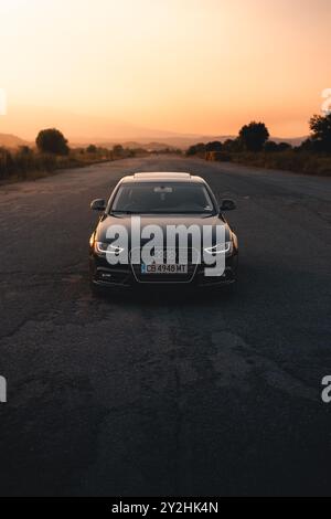 Bulgarien - 10 02 2024: Schwarzer Audi mitten auf einem Flughafen mit leuchtendem orangefarbenem Licht im Hintergrund. Stockfoto