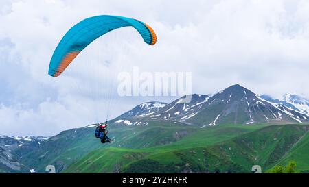 Tiflis, Georgien-Juni 06,2024 : Menschen, die zwischen den Bergen von Kasbegi Gleitschirmfliegen. Stockfoto