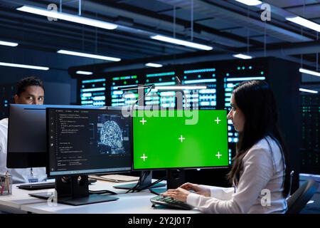 Team von Technikern, die Wartungsarbeiten am Green-Screen-Computer im Server-Hub durchführen, der für Workloads mit künstlicher Intelligenz verwendet wird. Teamwork-Mitarbeiter, die Rechenzentren neuronaler Netzwerke mit einem Modell-PC überprüfen Stockfoto