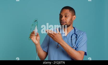 Männliche Krankenschwester, die ein medizinisches Unterrichtsvideo über die Verwendung von Handnebulizer für die Abgabe von Medikamenten auf Aerosolbasis macht. Medic präsentiert Inhalationsgerät für Lungenerkrankungen wie Lungenentzündung, Kamera A Stockfoto