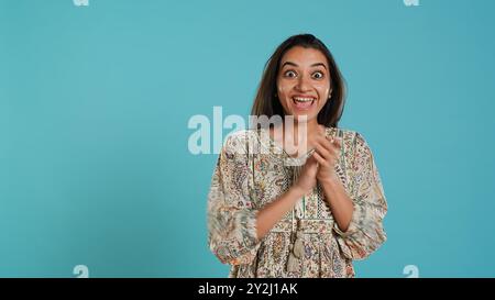 Fröhliche indianerin klatscht fröhlich an die Hände, ekstatisch über Leistungen. Aufgeregt, reagierend auf gute Nachrichten, jubelnd, applaudierend, isoliert über Studio-Hintergrund, Kamera A Stockfoto
