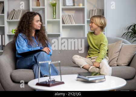 Blonder Junge, der vor Beginn der Sitzung mit einem Logopäden spricht Stockfoto