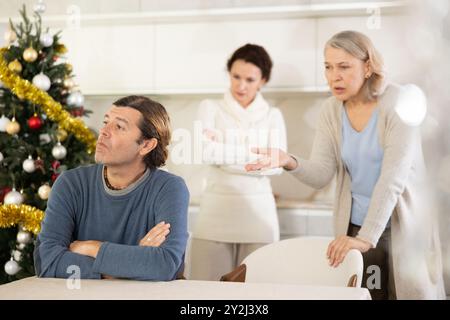 Ältere Mutter und Frau während des Familienstreits beschuldigen erwachsenen Mann am Heiligabend Stockfoto
