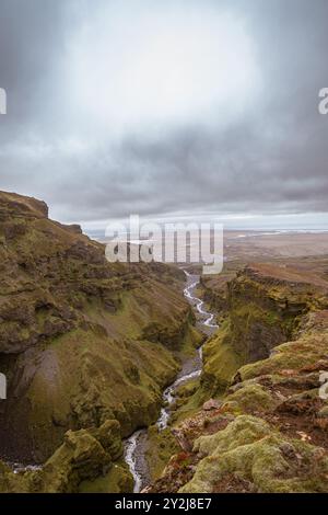 Atemberaubende Berge mit kaskadierenden Wasserfällen, die durch den üppigen Múlagljúfur Canyon in Islands rauer Landschaft fließen Stockfoto