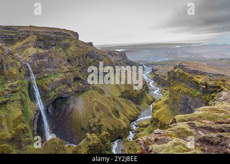 Atemberaubende Berge mit kaskadierenden Wasserfällen, die durch den üppigen Múlagljúfur Canyon in Islands rauer Landschaft fließen Stockfoto