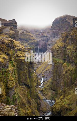 Atemberaubende Berge mit kaskadierenden Wasserfällen, die durch den üppigen Múlagljúfur Canyon in Islands rauer Landschaft fließen Stockfoto