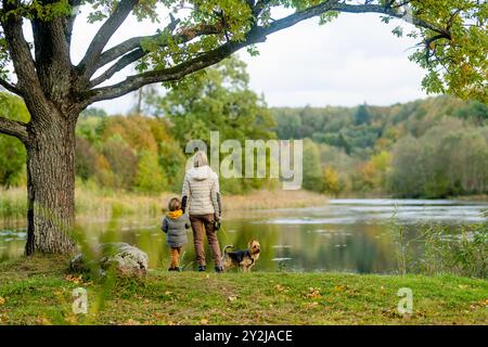 Mutter und ihr kleiner Sohn gehen im Spätherbst-Park mit ihrem Stammhund australischen Terrierhund. Herbstporträt von schwarzem und braunem reinrassigem Au Stockfoto